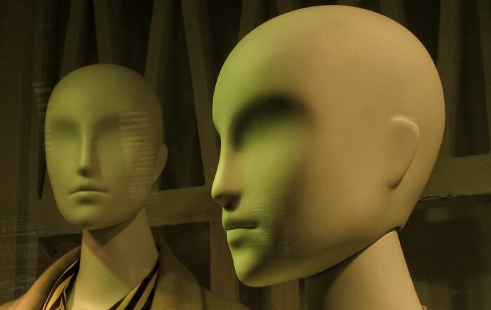 Two mannequins with weird, blank faces in a dimly lit setting at someone's home.