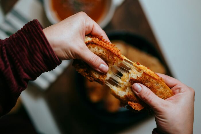 Hands pulling apart a grilled cheese sandwich with melting cheese, a weird thing people were not prepared to see.