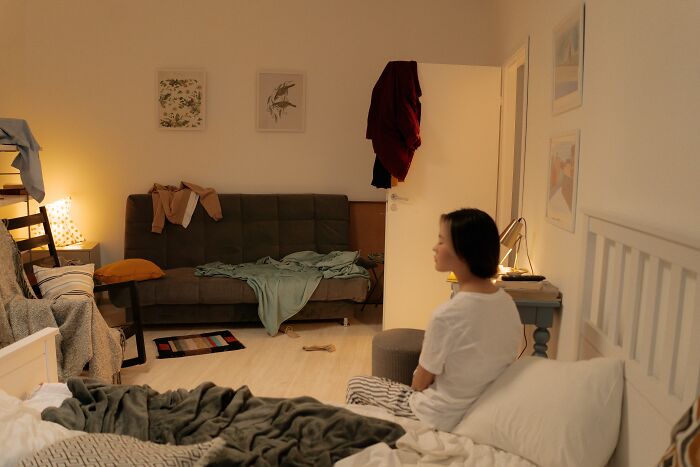 A woman sits in a messy room, highlighting weird things people were not prepared to see at someone's home.