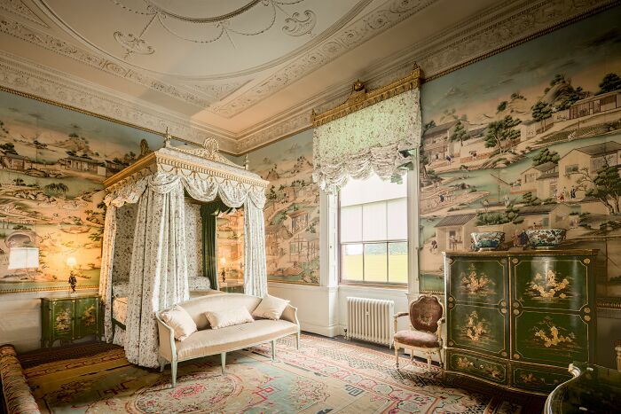 An ornate bedroom with a canopy bed and painted walls, showcasing weird things people were not prepared to see.