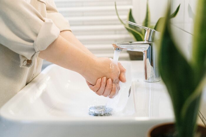 Hands washing under a faucet, highlighting weird things people were not prepared to see at someone’s home.