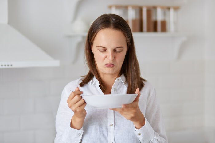 A woman with a disgusted expression holding a bowl, experiencing one of the weirdest things at home.