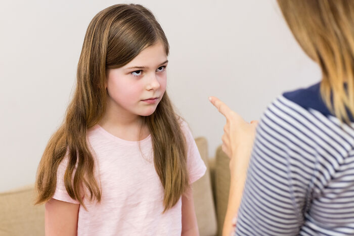 A girl with long hair looking annoyed while an adult points a finger at her, showing weird things at home.