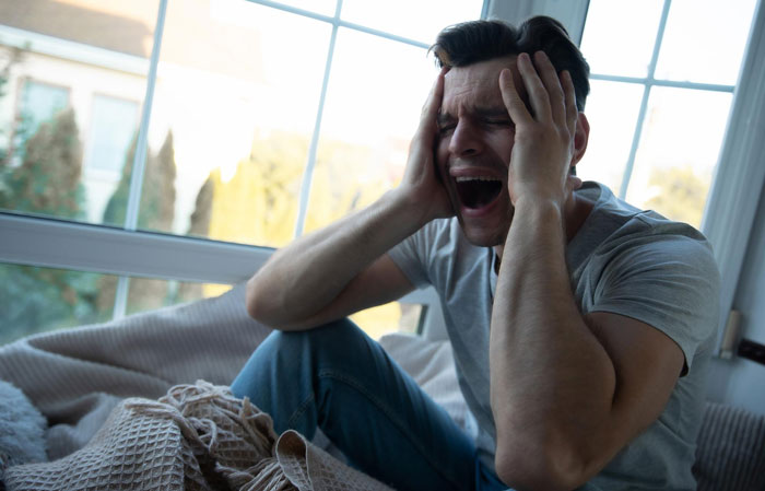 Distressed man, head in hands, screaming, feeling overwhelmed by parents attempts to ruin his reputation. Distressed man, head in hands, screaming, feeling overwhelmed by parents attempts to ruin his reputation.
