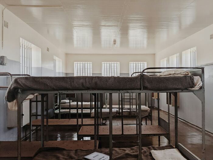Bunk beds in a sparse prison cell with barred windows