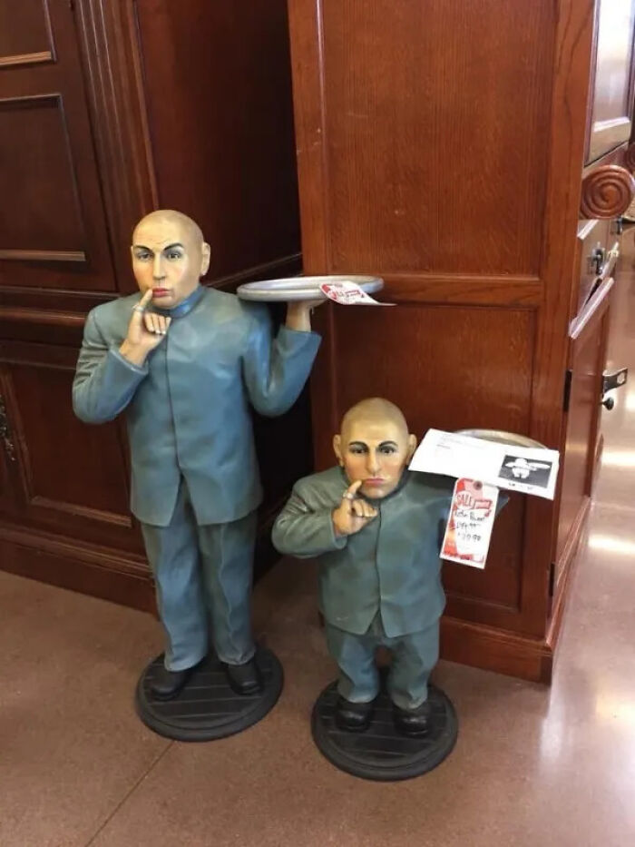 Two Mr. Bigglesworth statues, unhinged secondhand finds, standing in a store.