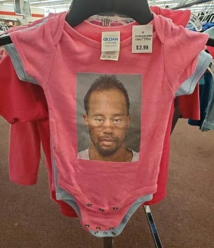 A baby onesie with unhinged secondhand finds, displaying a mugshot of Tiger Woods.