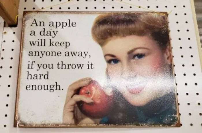 A vintage-style sign with a woman holding an apple, stating a funny saying, a cursed treasure secondhand find.