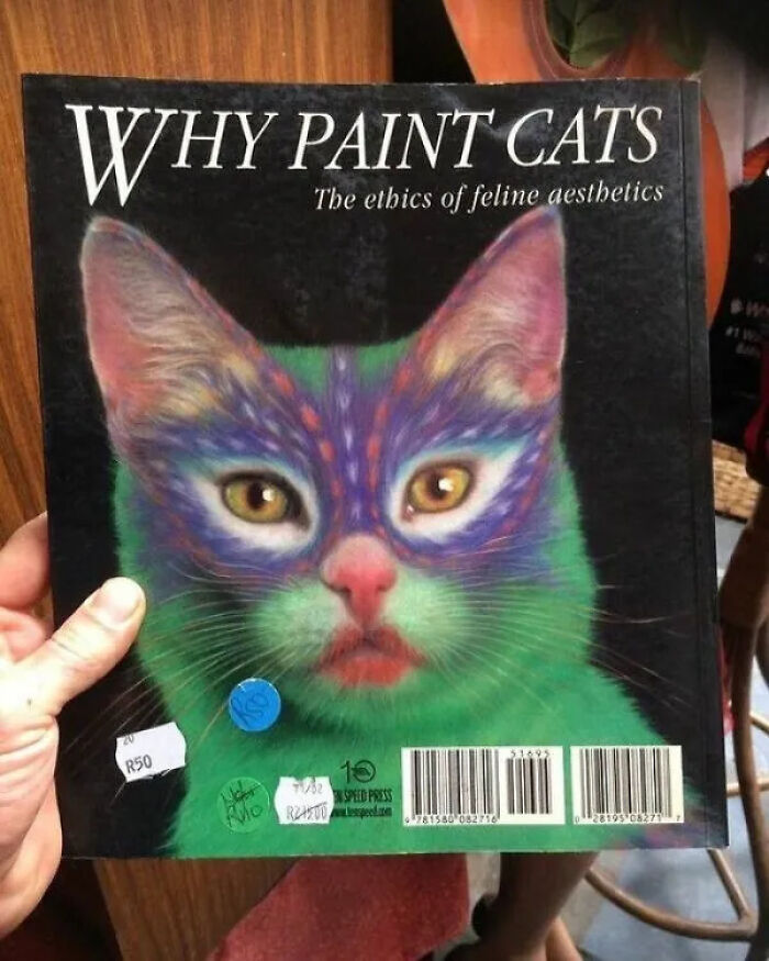 A hand holds a book titled Why Paint Cats, featuring a cat with vibrant, painted fur. A truly unhinged secondhand find.