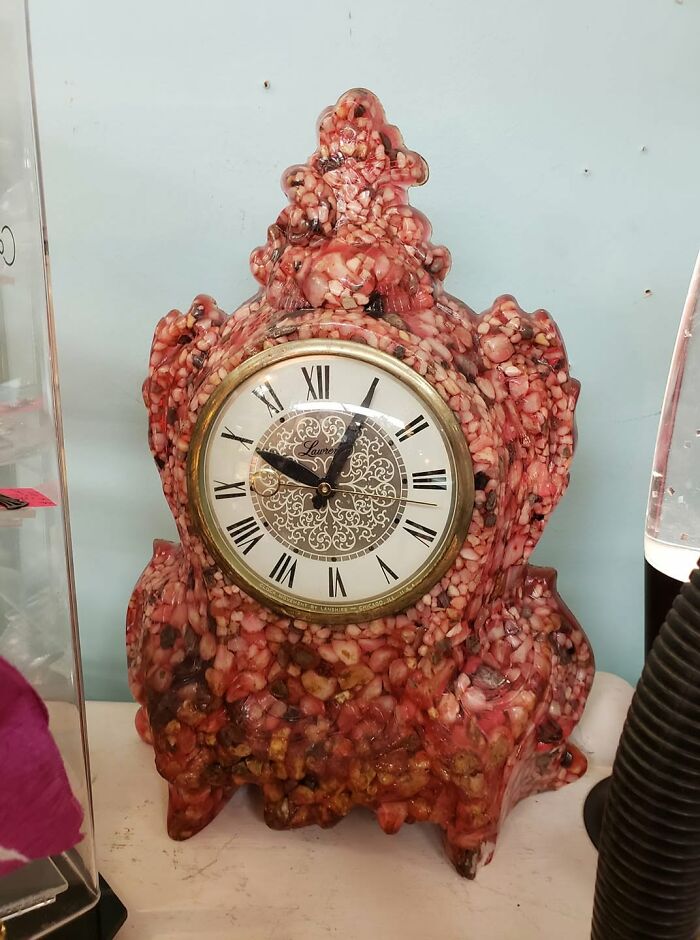 An unhinged secondhand mantel clock, seemingly made from a collection of teeth and gums, sitting on a shelf.