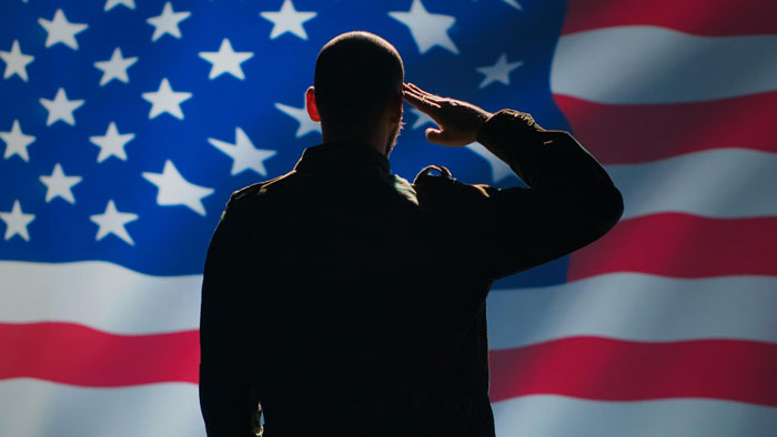 A soldier saluting in front of a US flag, hinting at a future war prediction from a time-traveler.