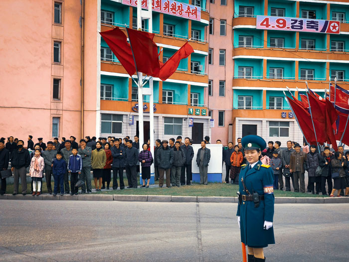 North Korean soldiers and civilians in a city square, potentially related to a time-traveler's war prediction.