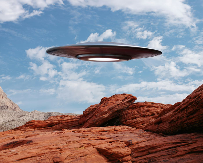 A UFO hovering over a desert landscape, suggesting an alien involvement in a time-traveler's war prediction.