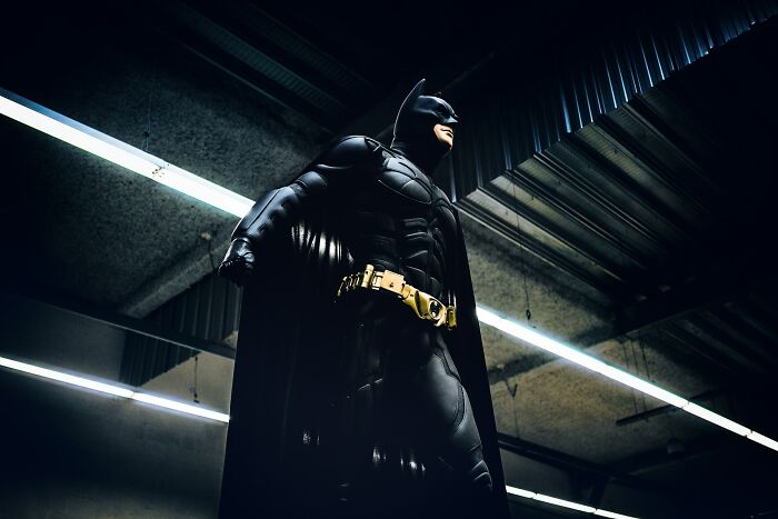Batman figure standing under ceiling lights, revealing new facts