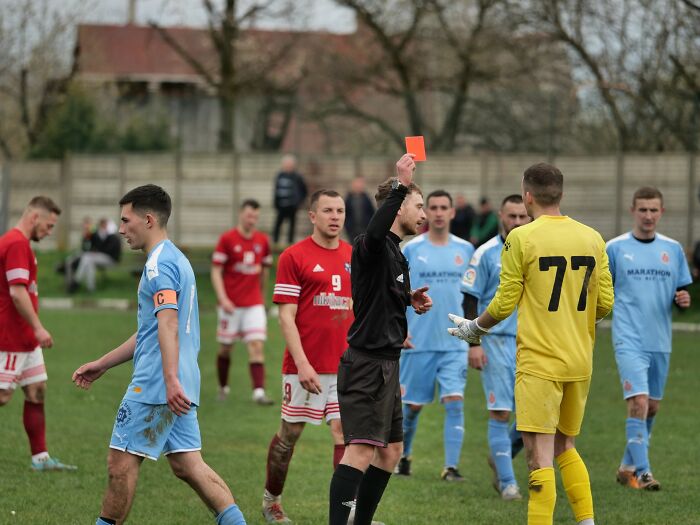 A referee shows a red card during a soccer match, highlighting new facts about sports rules