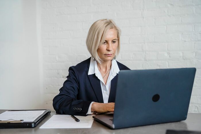 A blonde businesswoman working on a laptop at her desk, showcasing new facts about professional life