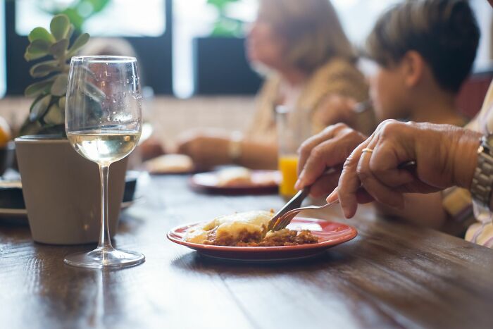 Close-up of hands eating food at a dinner table, representing new facts about dining etiquette