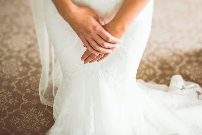 A close-up of a bride holding her hands over her white weddings dress