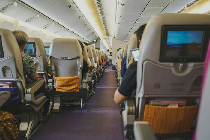 Interior cabin view with passengers seated in rows, showing a typical plane seatmate arrangement on a flight