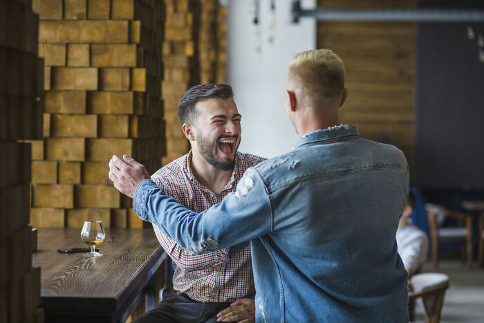 Two men greeting each other with laughter, relating to stories of divorced people