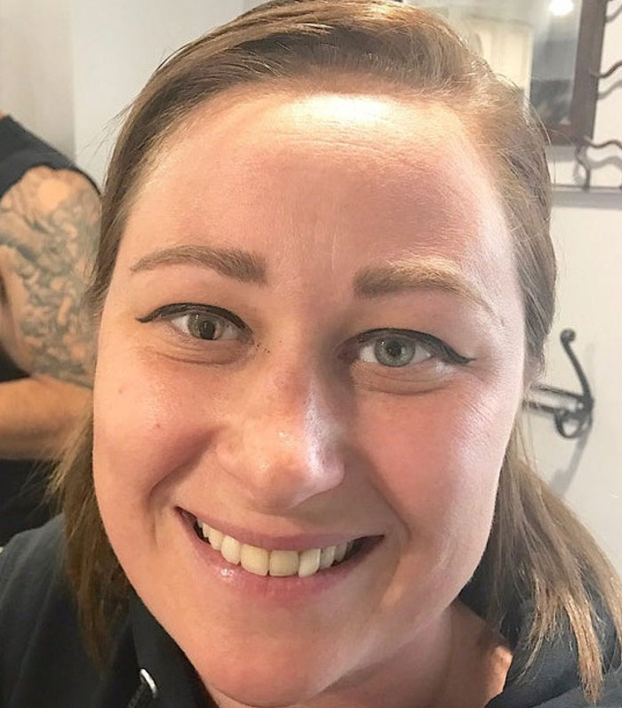 A smiling woman with heterochromia, one eye green and one eye brown, showcasing a body quirk.