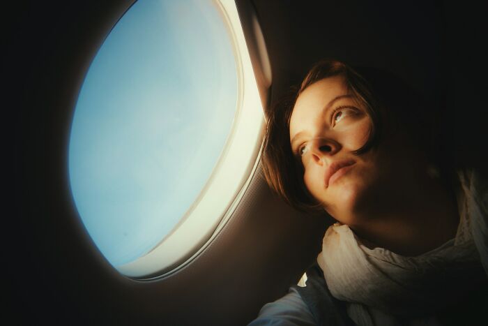 Woman looking out the window while enduring a plane seatmate from hell