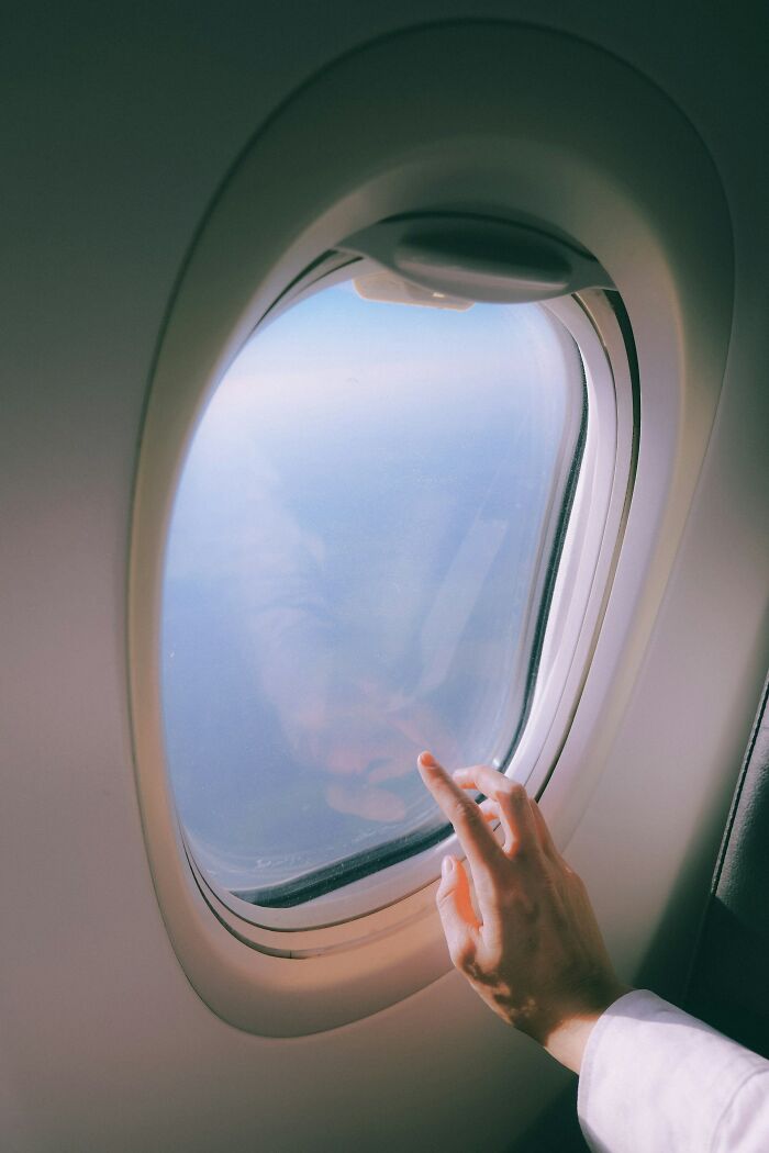 A hand points out an airplane window, showcasing things cabin crew deal with.