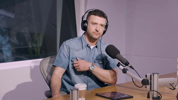 Justin Timberlake wearing headphones and speaking into a microphone during a podcast interview