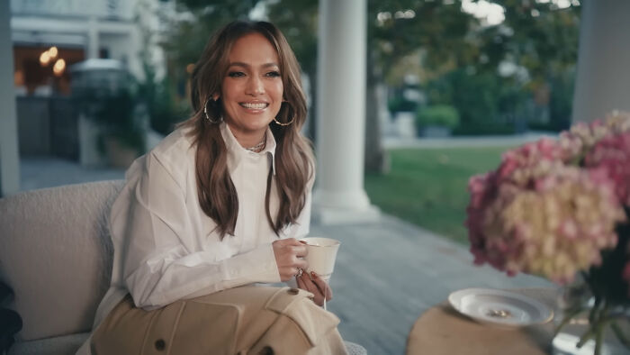 Jennifer Lopez smiling on an outdoor patio holding a teacup, showing a celebrity encounter setting