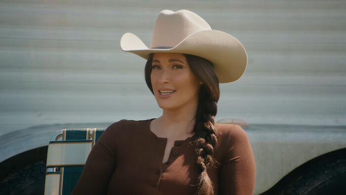 A woman wearing a beige cowboy hat and brown top, representing celebrity encounters in a country style.