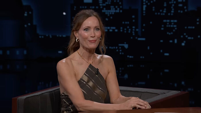 Leslie Mann sitting and smiling during an interview, sharing stories about celebrity encounters.
