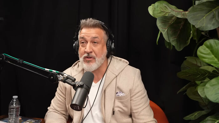 Joey Fatone speaking into a podcast microphone, sharing celebrity encounters experiences