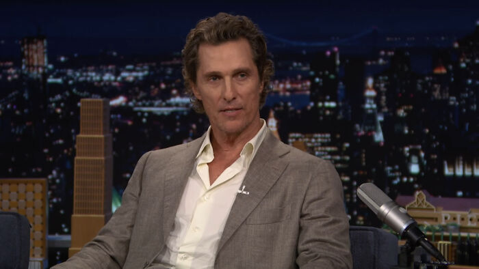 Matthew McConaughey in a suit on a talk show discussing celebrity encounters