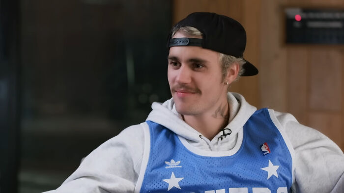 Justin Bieber wearing a backwards cap and jersey, discussing celebrity encounters