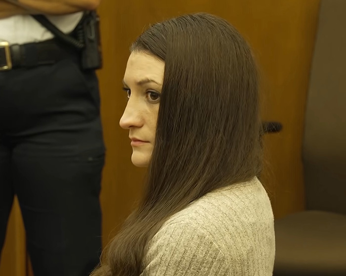 A close-up of Lindsay Clancy in court, viewed from the side, with an odd sticker on her wheelchair. A close-up of Lindsay Clancy in court, viewed from the side, with an odd sticker on her wheelchair.