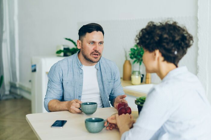 A man talking animatedly to a woman, discussing crazy and unhinged lies.