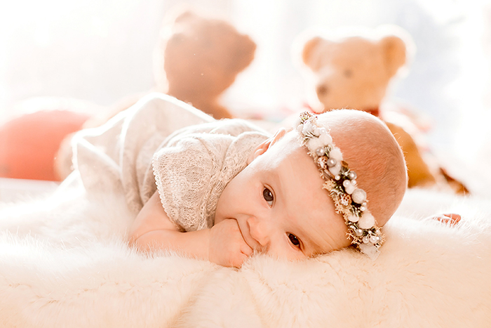 A baby with a floral headband lying on a white fluffy blanket, representing an ill girl in a story about an entitled kid and a heart monitor. A baby with a floral headband lying on a white fluffy blanket, representing an ill girl in a story about an entitled kid and a heart monitor.