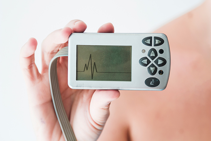 Close-up of a heart monitor being held, displaying a heartbeat on its screen, illustrating an ill girl's device. Close-up of a heart monitor being held, displaying a heartbeat on its screen, illustrating an ill girl's device.