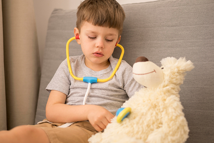 An entitled kid plays with a toy stethoscope on a teddy bear, mirroring the heart monitor he wants to steal. An entitled kid plays with a toy stethoscope on a teddy bear, mirroring the heart monitor he wants to steal.