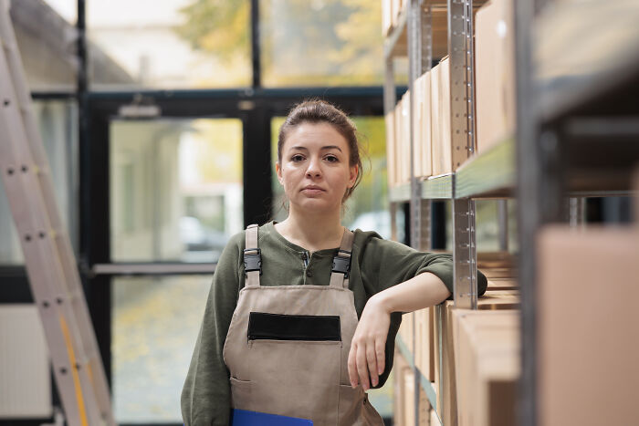 A determined female worker in a warehouse, speaking up on subtle sexism in male-dominated fields