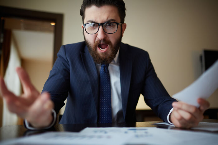 An angry boss shouting at work, showing signs that the economy is in trouble.