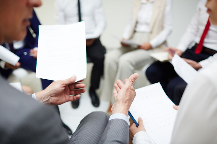 Business professionals holding papers and discussing work strategies in a struggling economy.