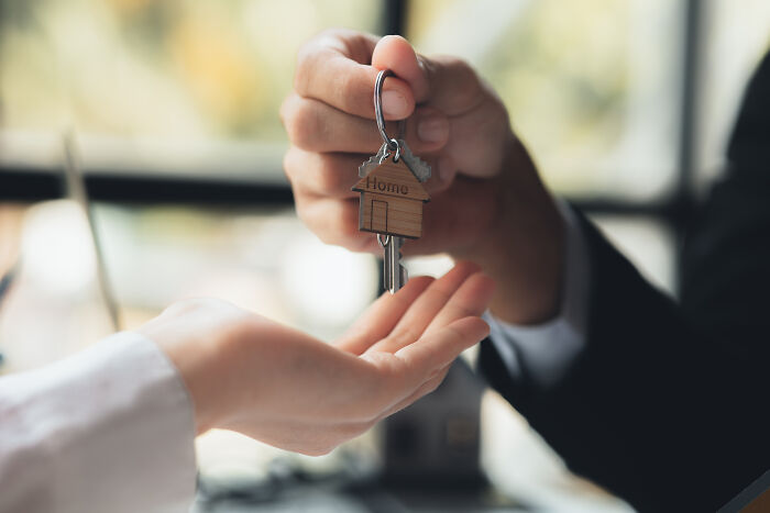 Hands passing a key, symbolizing home buying activity in the current economy.
