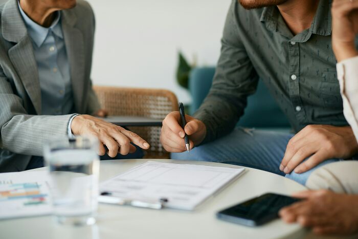 People discussing financial documents at a table, highlighting financial decisions during a difficult economy.