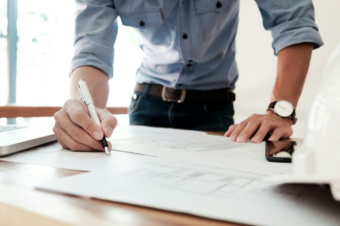 An architect drawing plans at work, highlighting the role of professional services in the economy.