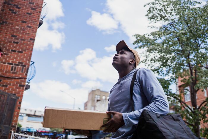 A delivery worker carrying a package on the street, illustrating hard work in a changing economy.