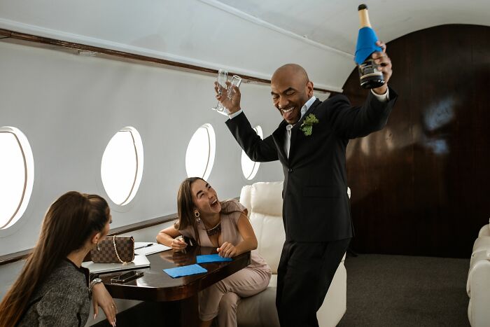 People celebrating on a private plane, highlighting class differences in the economy.