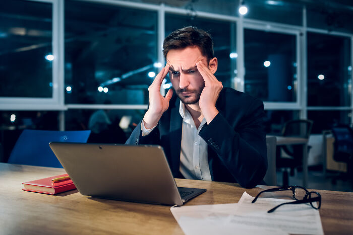 A stressed businessman looking at his laptop, representing satisfying stories of overcoming challenges.