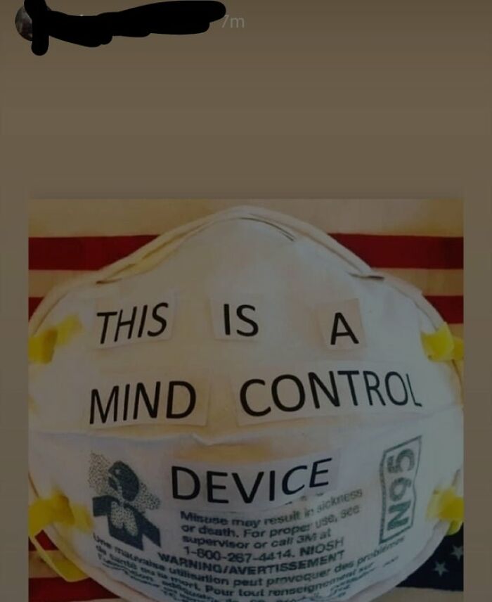 An N95 mask with the words This Is A Mind Control Device taped to it, showcasing unhinged thoughts.