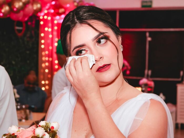 A bride wiping tears from her eyes at a wedding, experiencing a wild turn of heartfelt emotions during her special day.